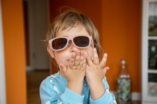 portrait of happy smiling adorable toddler in baby sunglasses. cheerful child send air kiss