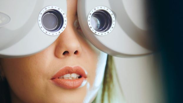 Ophthalmology clinic - woman checks vision by modern equipment - eyes exam, telephoto, close up