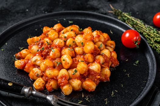 Portion of Italian Gnocchi potato pasta with tomato sauce. Black background. Top view.