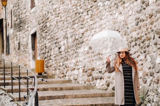 beautiful romantic girl in a coat and hat with a transparent umbrella in Annecy. France. The girl in the hat in France.