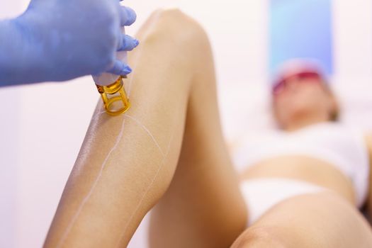 Woman receiving legs laser hair removal at a beauty center. Laser depilation treatment in an aesthetic clinic.