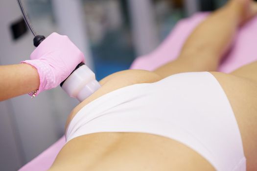 Middle-aged woman receiving anti-cellulite treatment with radiofrequency machine in an aesthetic clinic.