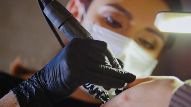 Manicurist in medical mask doing manicure in beauty shop, close up