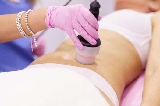 Middle-aged woman receiving anti-cellulite treatment with radiofrequency machine in an aesthetic clinic.