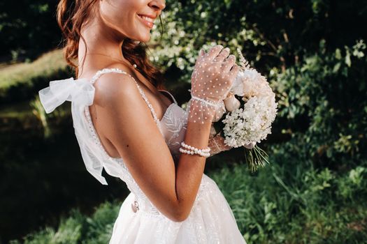 portrait of an elegant bride in a white dress with a bouquet in nature in a nature Park.Model in a wedding dress and gloves and with a bouquet .Belarus.