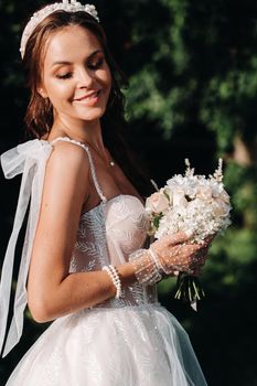 portrait of an elegant bride in a white dress with a bouquet in nature in a nature Park.Model in a wedding dress and gloves and with a bouquet .Belarus.
