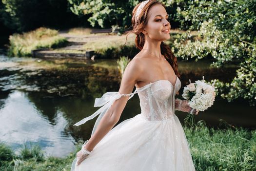 portrait of an elegant bride in a white dress with a bouquet in nature in a nature Park.Model in a wedding dress and gloves and with a bouquet .Belarus.