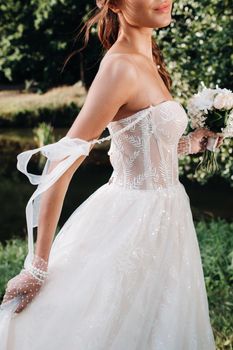 portrait of an elegant bride in a white dress with a bouquet in nature in a nature Park.Model in a wedding dress and gloves and with a bouquet .Belarus.