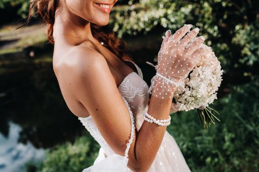 portrait of an elegant bride in a white dress with a bouquet in nature in a nature Park.Model in a wedding dress and gloves and with a bouquet .Belarus.