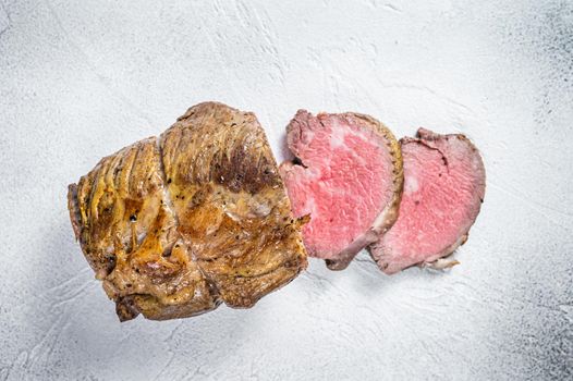 Roast beef meat fillet on kitchen table. White background. Top view.