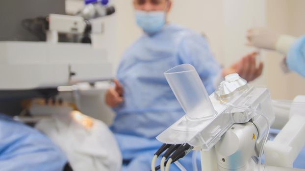 Surgeon using the microscope makes the operation - high technology health care medicine, de-focused