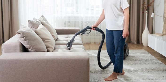 Housewife Cleaning Sofa With a Vacuum Cleaner