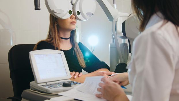 Ophthalmology - white woman checks vision in an ophthalmologist room - medicine high technology, telephoto