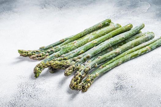 Frozen cold asparagus on a old kitchen table. White background. Top view.