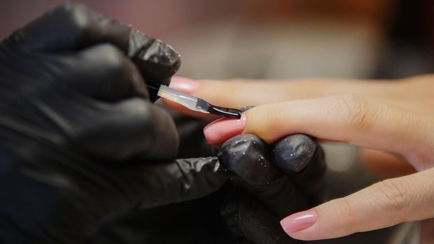 Macro view of polishing nails - female get professional manicure in beauty shop, horizontal