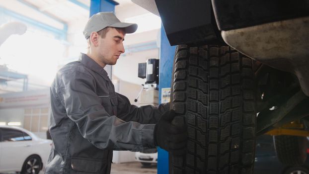 Garage automobile service - a mechanic working the wheel, close up, horizontal