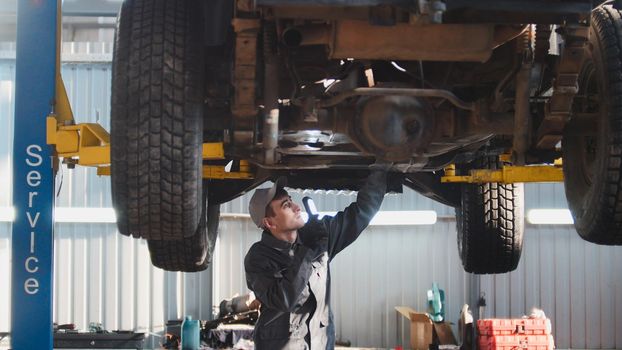 Car service - a mechanic checks the suspension of SUV, wide angle, horizontal