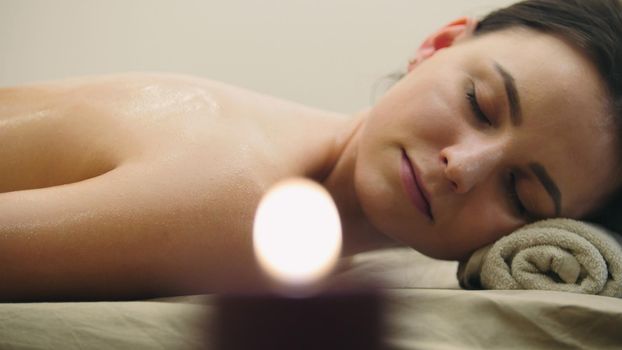 Young woman lying on massage table at spa salon, close up