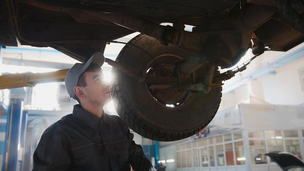 Garage automobile service - a mechanic checks the suspension, backlight, close up