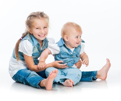 two cute sisters in the same clothes in studio on white