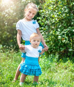 two lovely sisters in a meadow on a sunny summer day