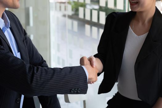 Happy caucasia male and asian female hand shaking, successful businessman handshake after good deal for both companies, business merger and acquisition concept.