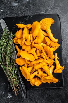 Raw wild Chanterelles mushrooms on a marble board. Black background. Top view.