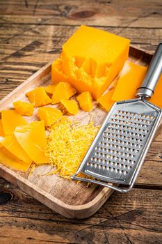 Cheddar Cheese Grated and diceded in a wooden tray. wooden background. Top view.