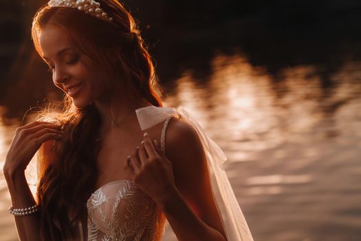 An elegant bride in a white dress enjoys nature at sunset.Model in a wedding dress in nature in the Park.Belarus.