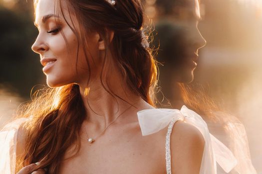 An elegant bride in a white dress enjoys nature at sunset.Model in a wedding dress in nature in the Park.Belarus.