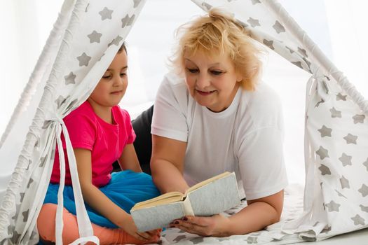 great grandmother and great granddaughter reading a book together