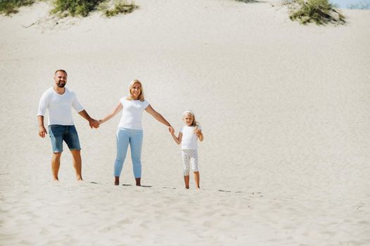 A happy family of three on the sand dunes of the Baltic sea near the city of Nida.Family trip to Europe.Lithuania.