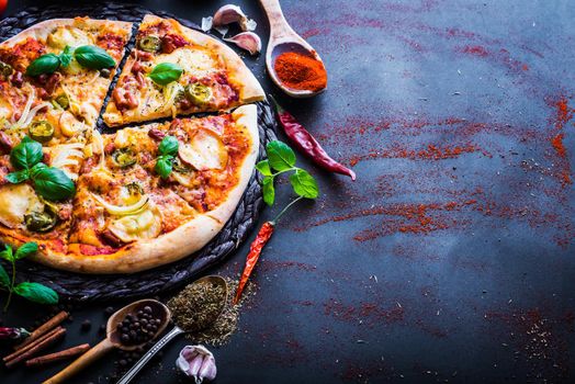 tasty pizza on a black background with spices and herbs