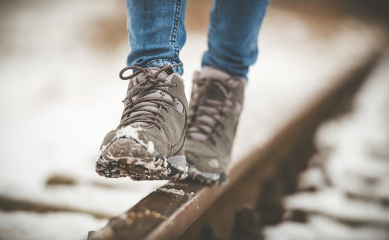 girl in boots walking on rails in winter