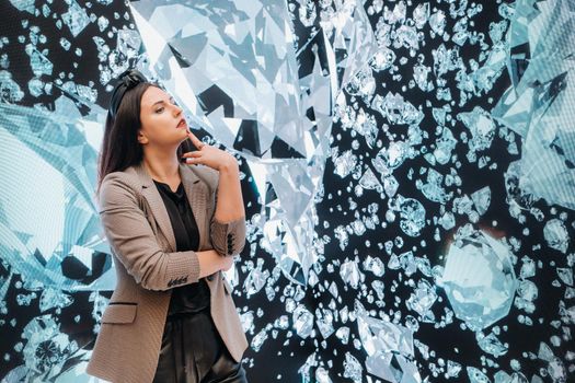 A girl in black pants and a jacket on a background of diamonds.