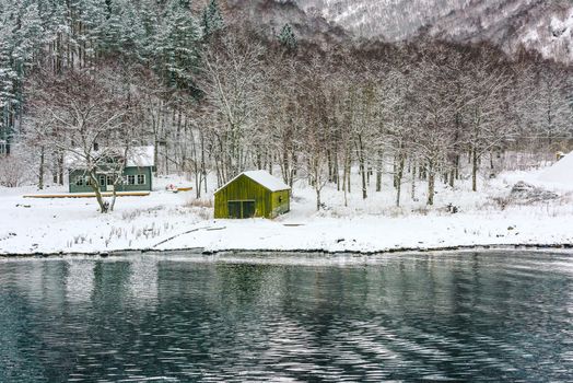 wooden houses on the banks of the Norwegian fjord, beautiful mountain landscape in winter