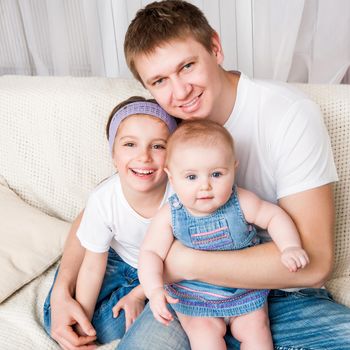 attractive young father with two daughters sitting at home