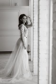 A luxurious bride in a wedding dress in the morning in her interior.Black and white photo.