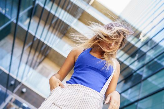 View from below of young girl moving her hair wild outdoors