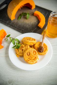 sweet lush pumpkin pancakes with honey in a plate on a wooden table
