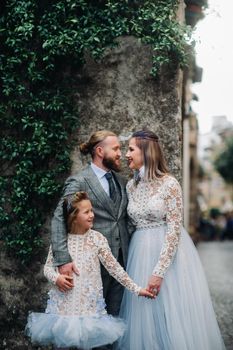 A happy young family walks through the old town of Sirmione in Italy.Stylish family in Italy on a walk.