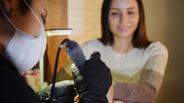 Professional manicure for smiling young woman in beauty salon, close up