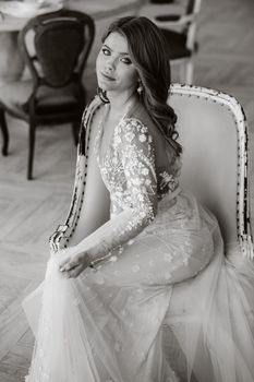 A luxurious bride in a wedding dress in the morning in her interior.Black and white photo.