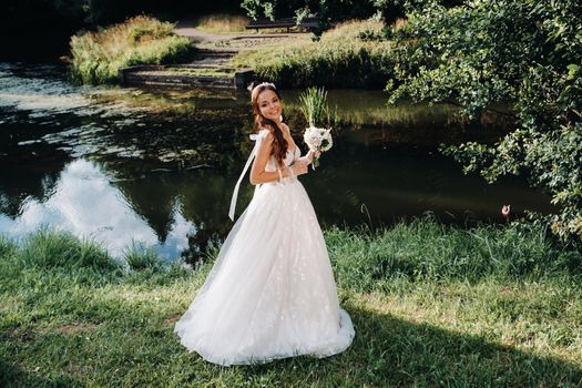 portrait of an elegant bride in a white dress with a bouquet in nature in a nature Park.Model in a wedding dress and gloves and with a bouquet .Belarus.