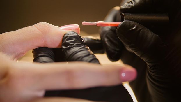 Macro view of nail polishing - female get professional manicure in beauty salon, horizontal