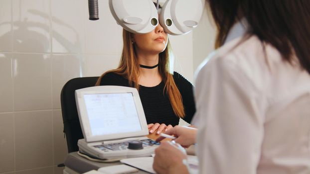 Ophthalmology - eyes clinic concept - optometrist and patient doing exam vision, telephoto