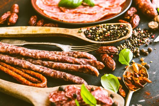 various sausages with spices on black table