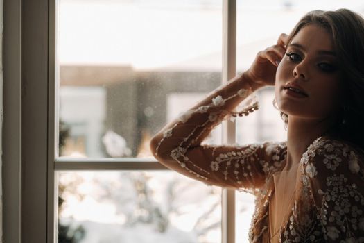 A luxurious bride in a wedding dress in the morning in her interior.