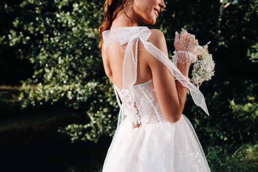 portrait of an elegant bride in a white dress with a bouquet in nature in a nature Park.Model in a wedding dress and gloves and with a bouquet .Belarus.