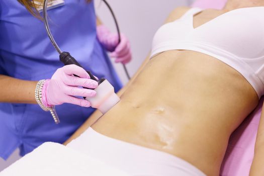 Middle-aged woman receiving anti-cellulite treatment with radiofrequency machine in an aesthetic clinic.